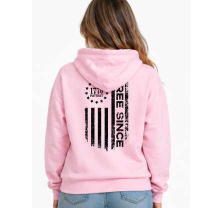Back view of a light pink pullover hoodie with a black distressed Free Since flag graphic and 1776 Patriot emblem