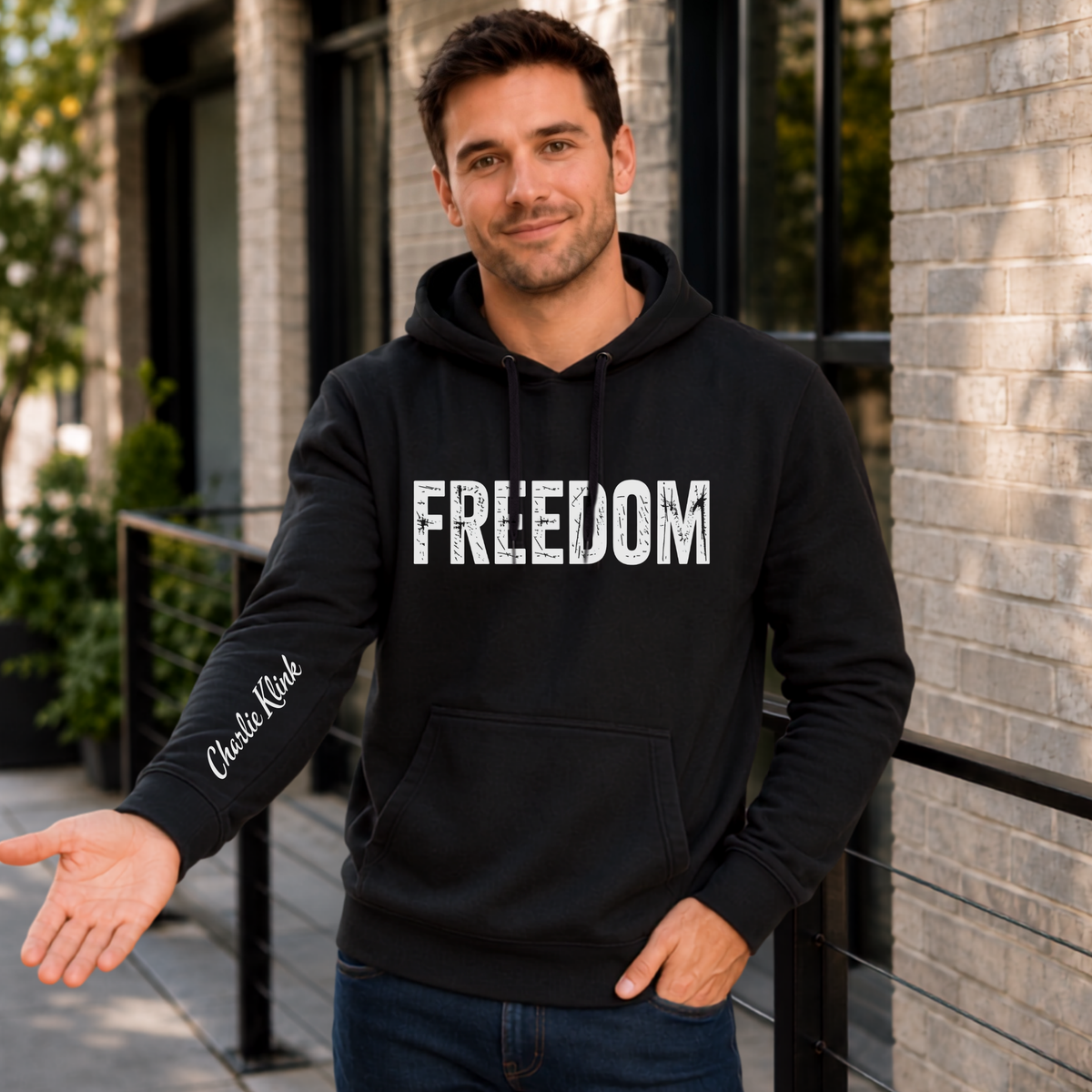 Man wearing a black FREEDOM hoodie with Charlie Kirk signature printed on the inside sleeve.