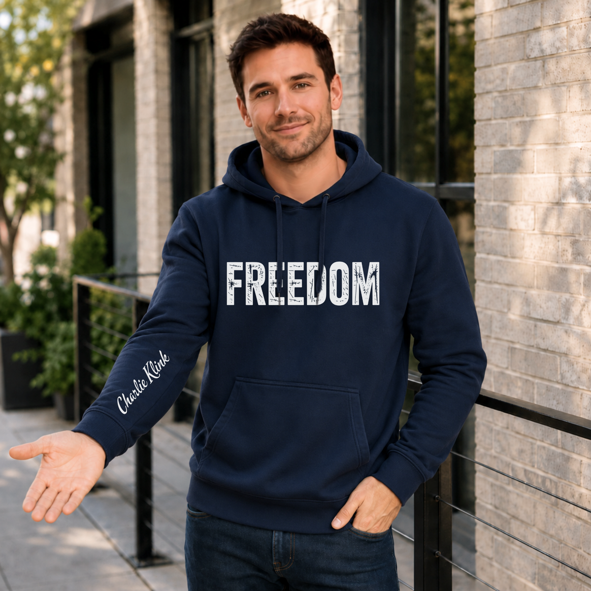 Man wearing a navy FREEDOM hoodie with the Charlie Kirk signature printed on the inside sleeve.