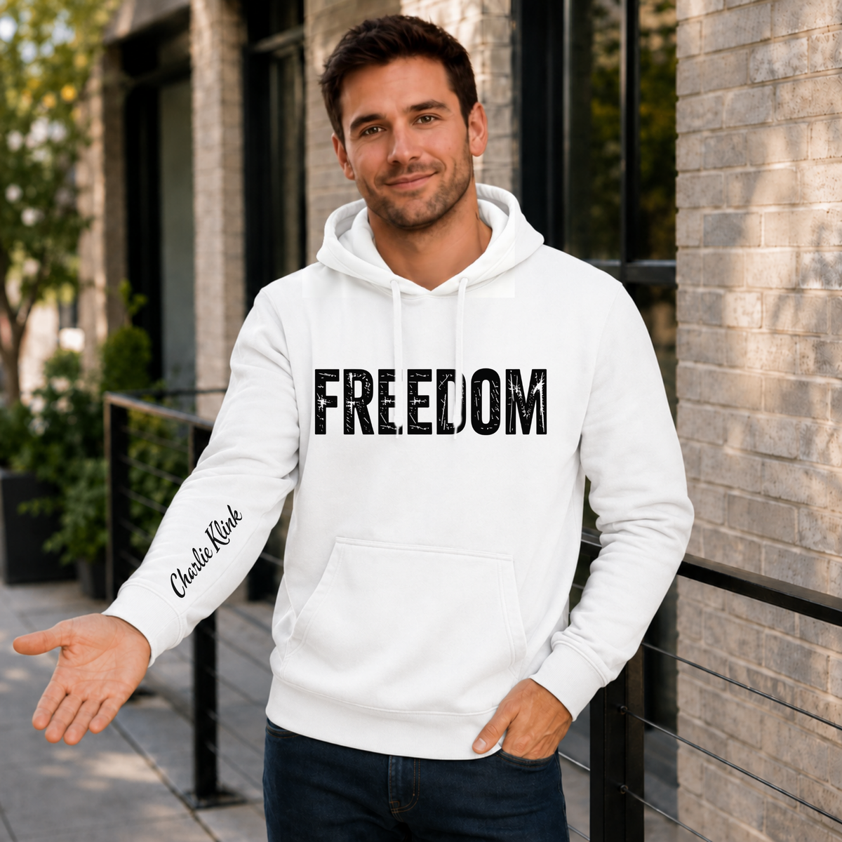 Man wearing a white FREEDOM hoodie with Charlie Kirk signature printed on the inside sleeve.
