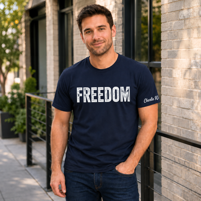 Man wearing a navy FREEDOM T-shirt with Charlie Kirk signature printed on the inside sleeve.