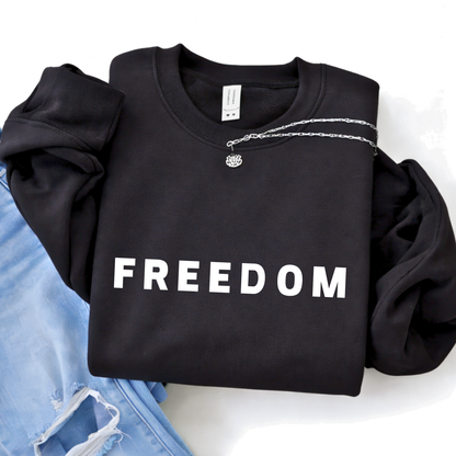 Black FREEDOM sweatshirt folded flat lay with jeans and accessories