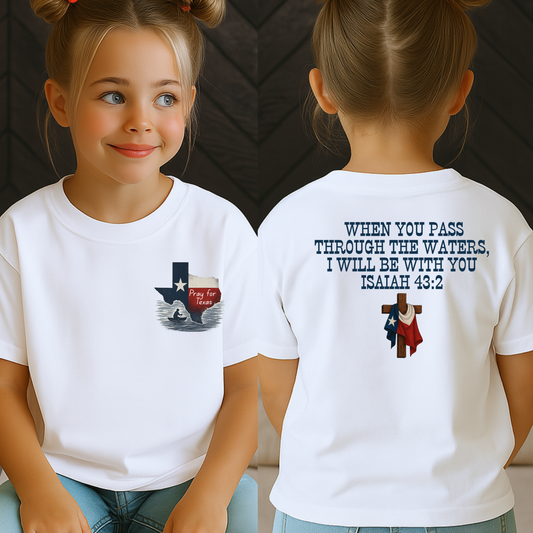 Front and back view of a young girl wearing a white Christian T-shirt featuring a “Pray for Texas” design with a flood scene inside the Texas state outline on the front, and the Bible verse Isaiah 43:2 on the back with a wooden cross and Texas flag. Youth faith-based support shirt for Texas flood relief.