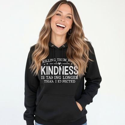 Laughing woman modeling a black Killing Them With Kindness hoodie with white lettering against a white background.
