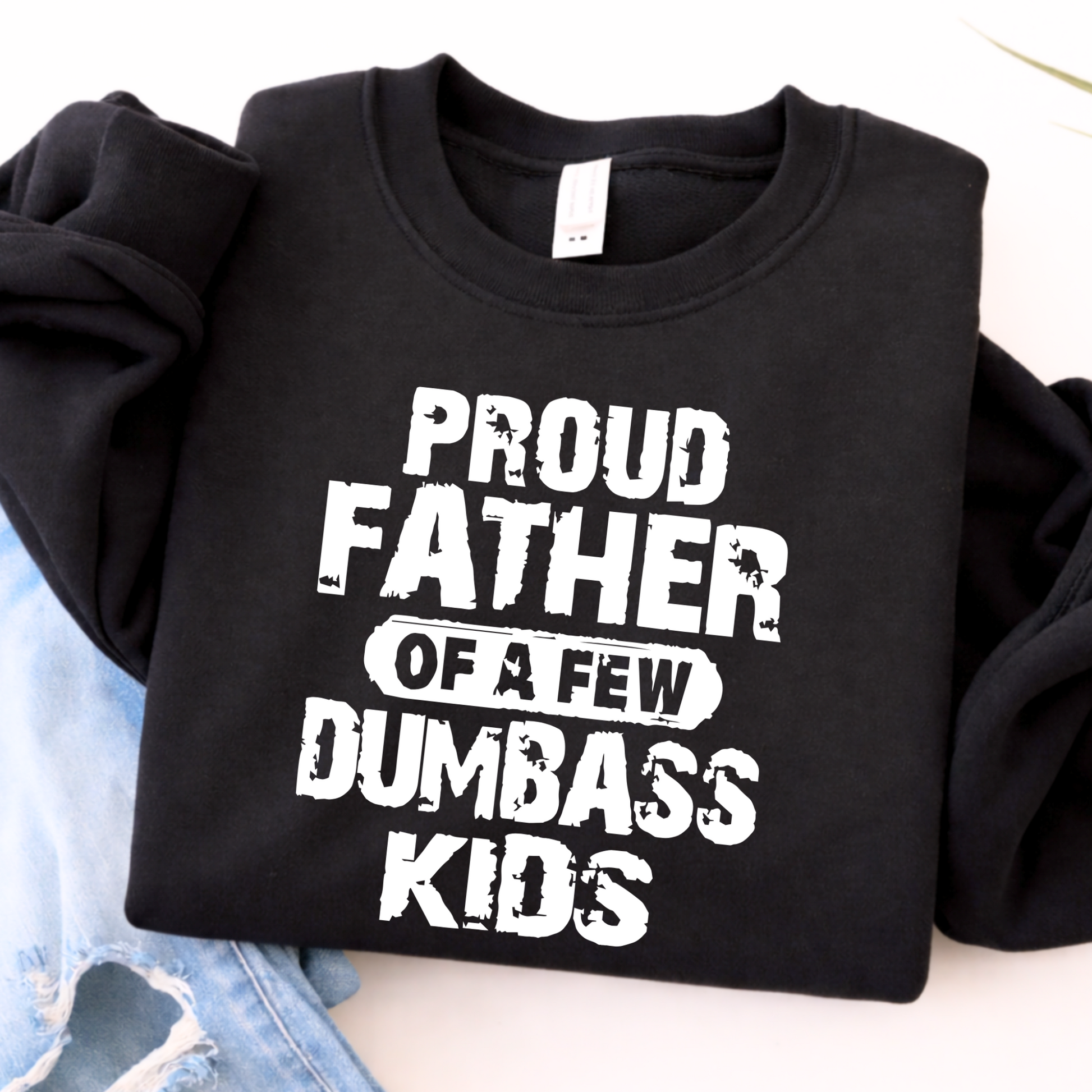 Black sweatshirt with white text 'Proud Father of a Few Dumbass Kids' on a light background.