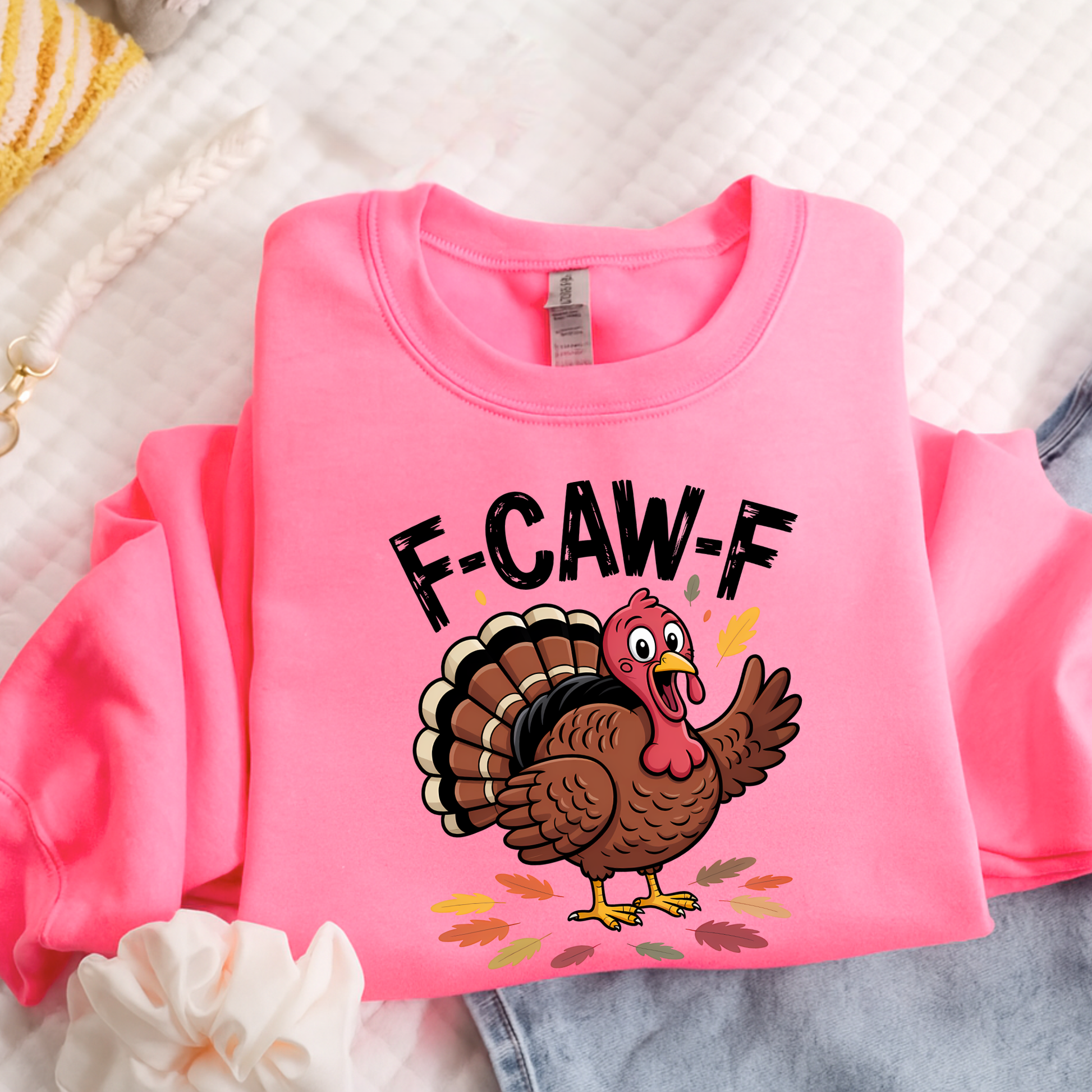 Bright pink sweatshirt folded with funny turkey graphic and fall leaves