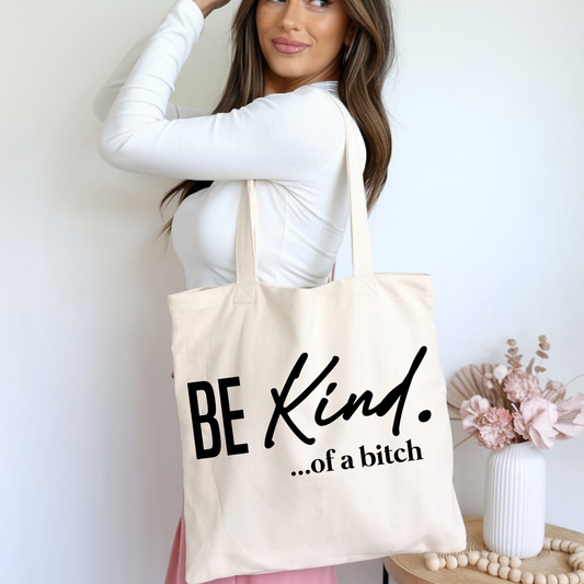 Funny tote bag with “Be Kind ...of a Bitch” text, held by woman in casual outfit