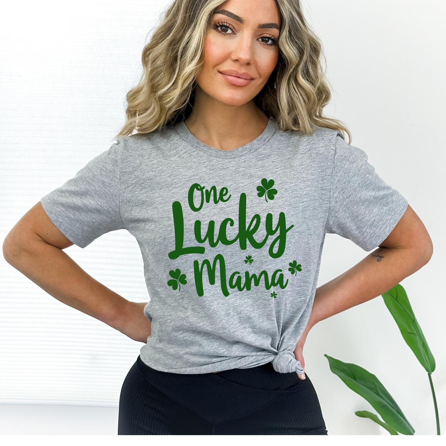 A stylish gray t-shirt with "One Lucky Mama" in green script, decorated with shamrocks. Perfect for moms celebrating St. Patrick’s Day in a cute and festive way.