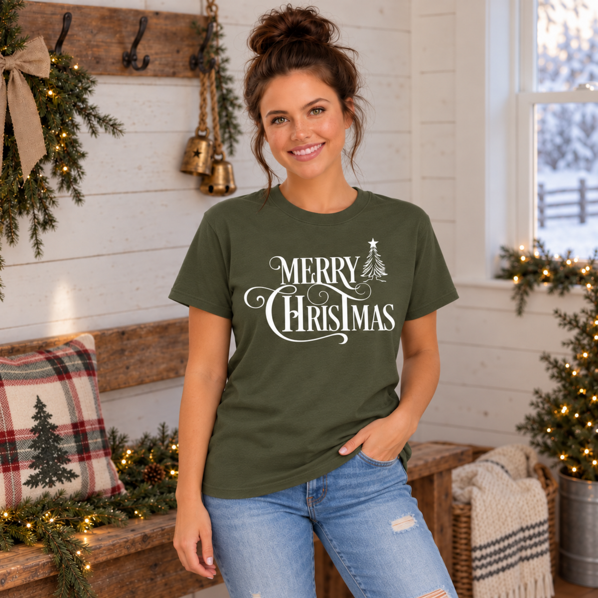Military green Merry Christmas graphic T-shirt worn by a model in a rustic room with festive decorations.