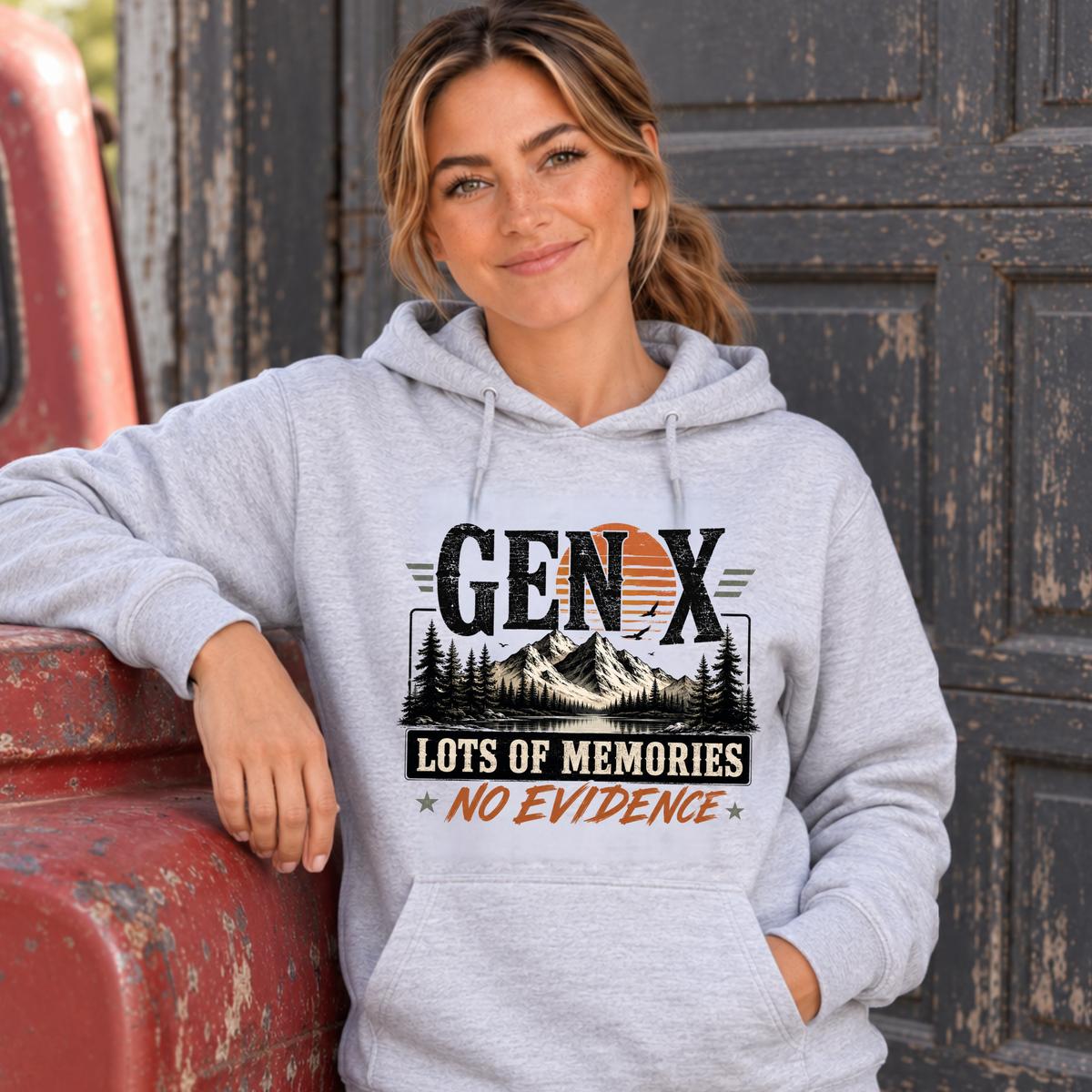 Women's sports gray Gen X hoodie with Lots of Memories No Evidence mountain graphic, modeled beside a vintage red truck
