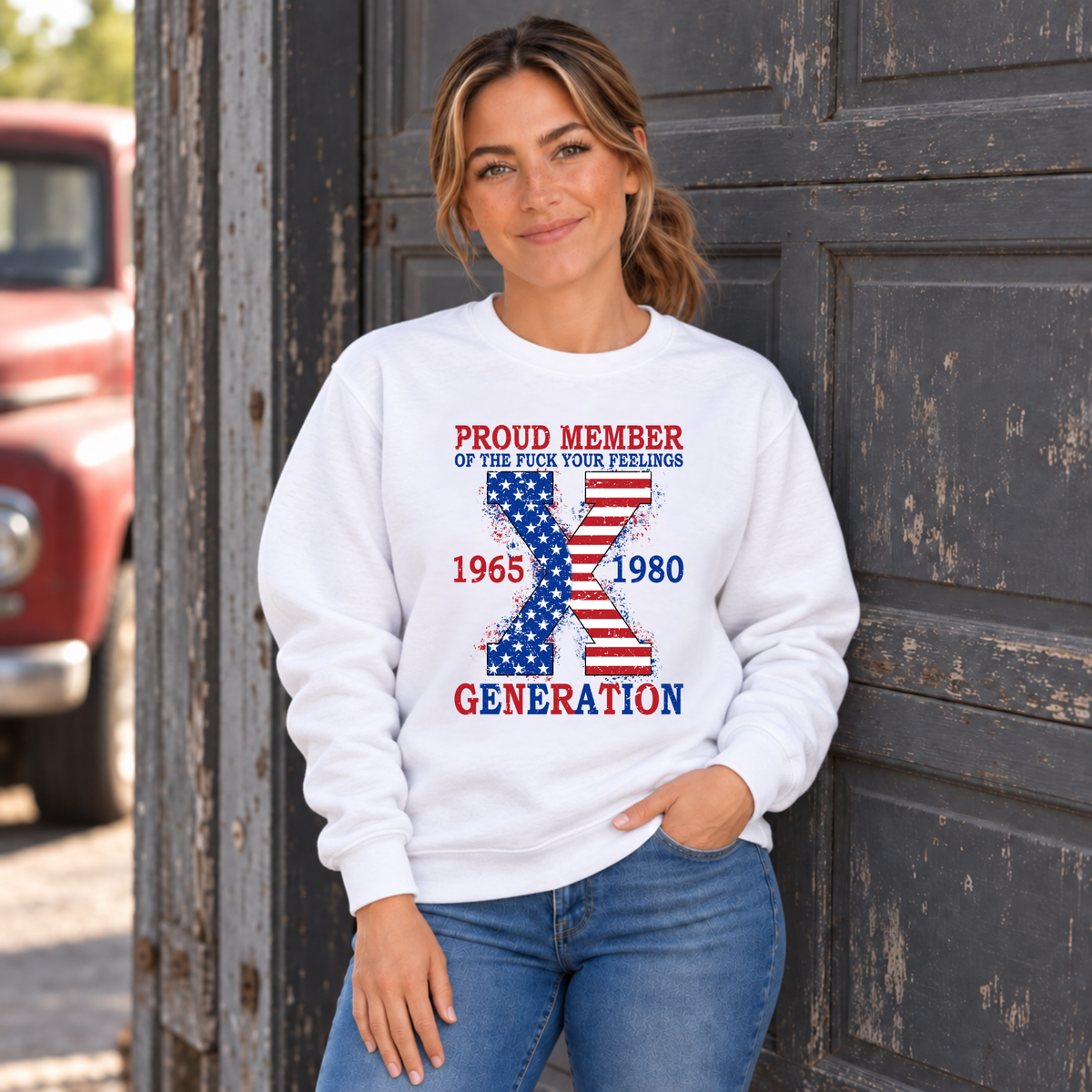 Women's white sweatshirt with American flag Generation X 1965–1980 design, modeled beside a vintage red truck