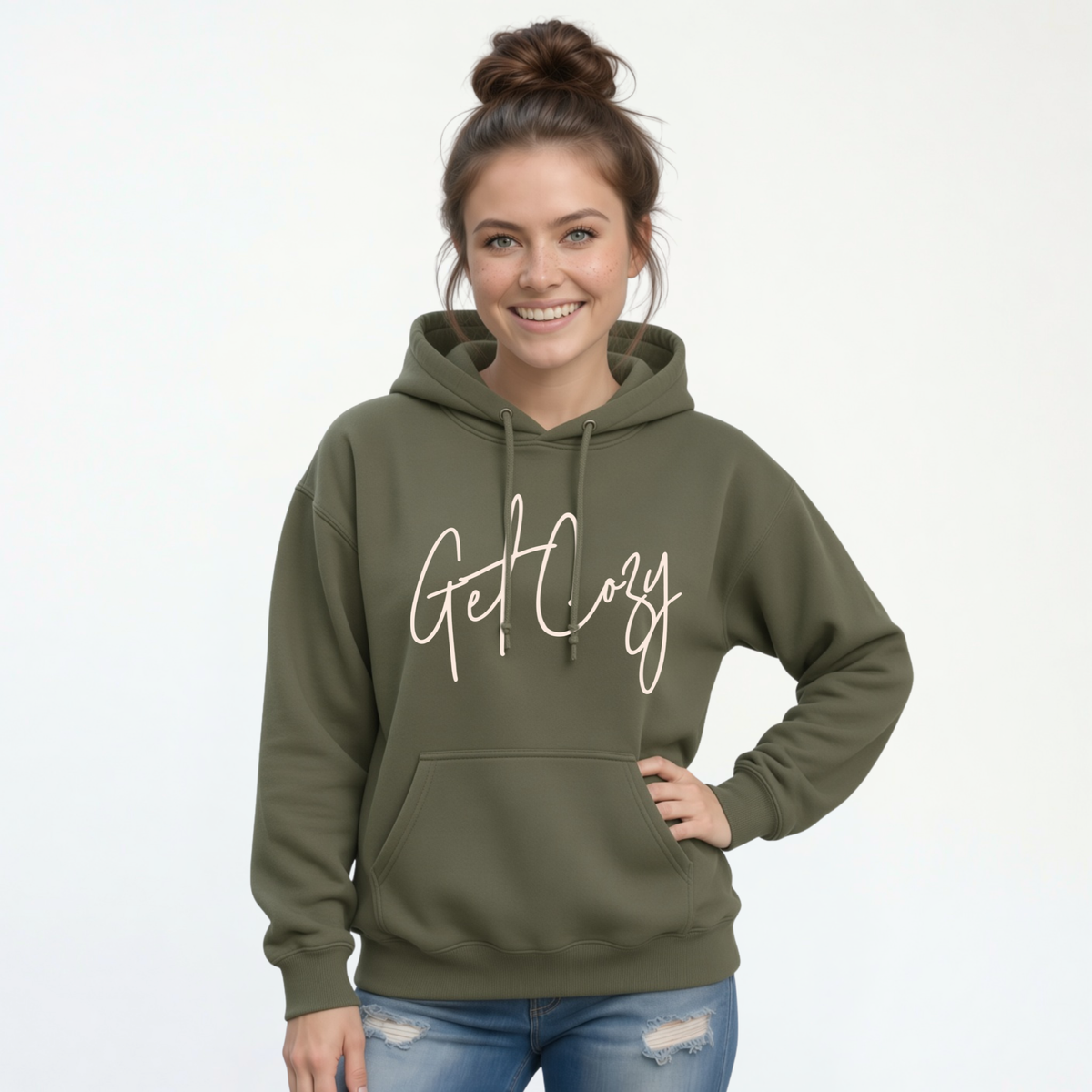 Woman wearing a military green pullover hoodie with a minimalist Get Cozy script design, paired with blue jeans on a white background.