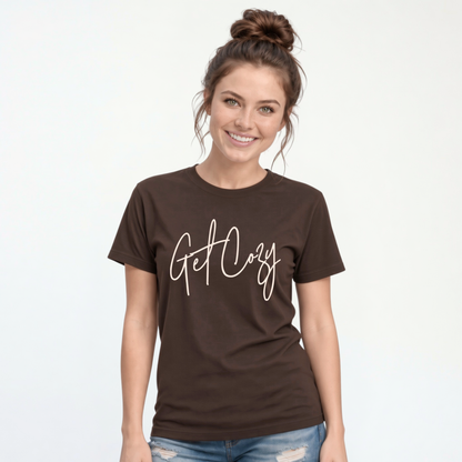 Woman wearing a brown T-shirt with a minimalist Get Cozy script design, paired with blue jeans on a white background.