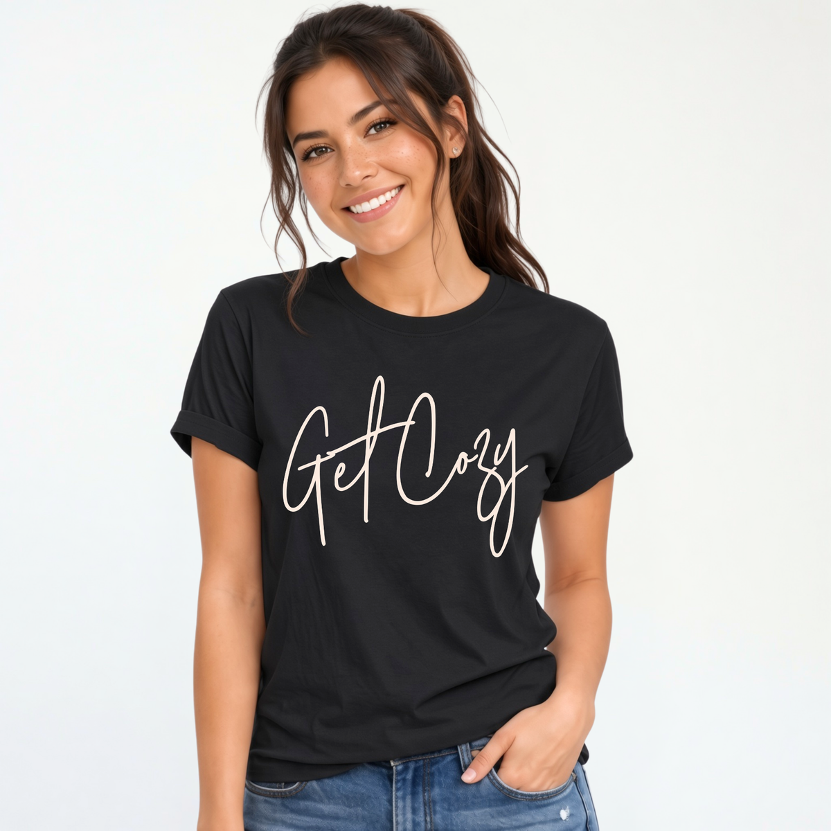 Woman wearing a black T-shirt with a minimalist Get Cozy script design, paired with blue jeans on a white background.