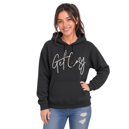 Woman wearing a black pullover hoodie with a minimalist Get Cozy script design, paired with distressed blue jeans on a white background.