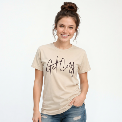 Woman wearing a sand T-shirt with a minimalist Get Cozy script design, paired with blue jeans on a white background.