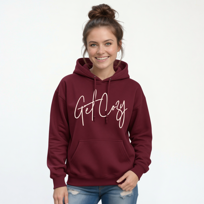 Woman wearing a maroon pullover hoodie with a minimalist Get Cozy script design, paired with blue jeans on a white background.