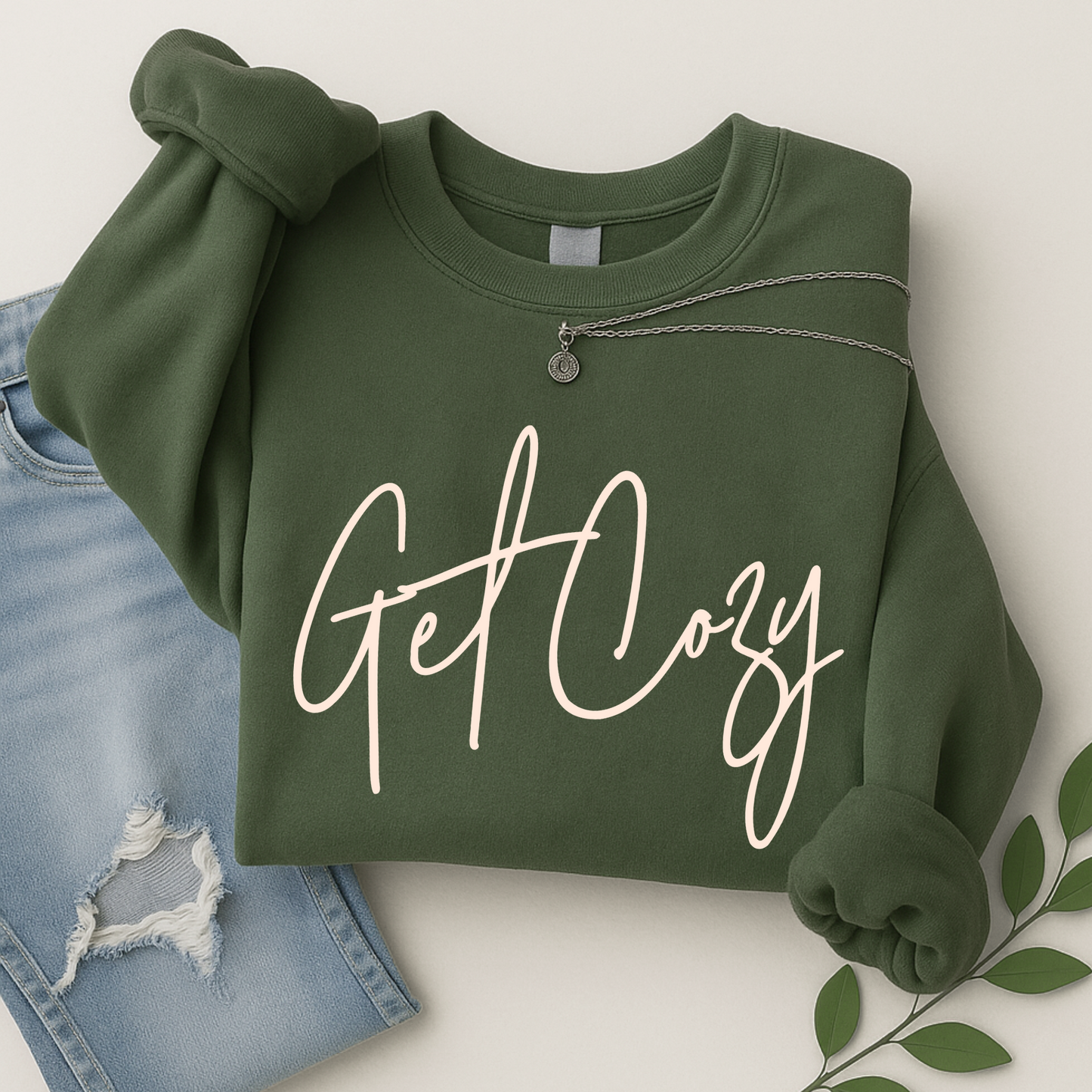 Green sweatshirt with 'Get Cozy' text on a white background with denim and leaves.