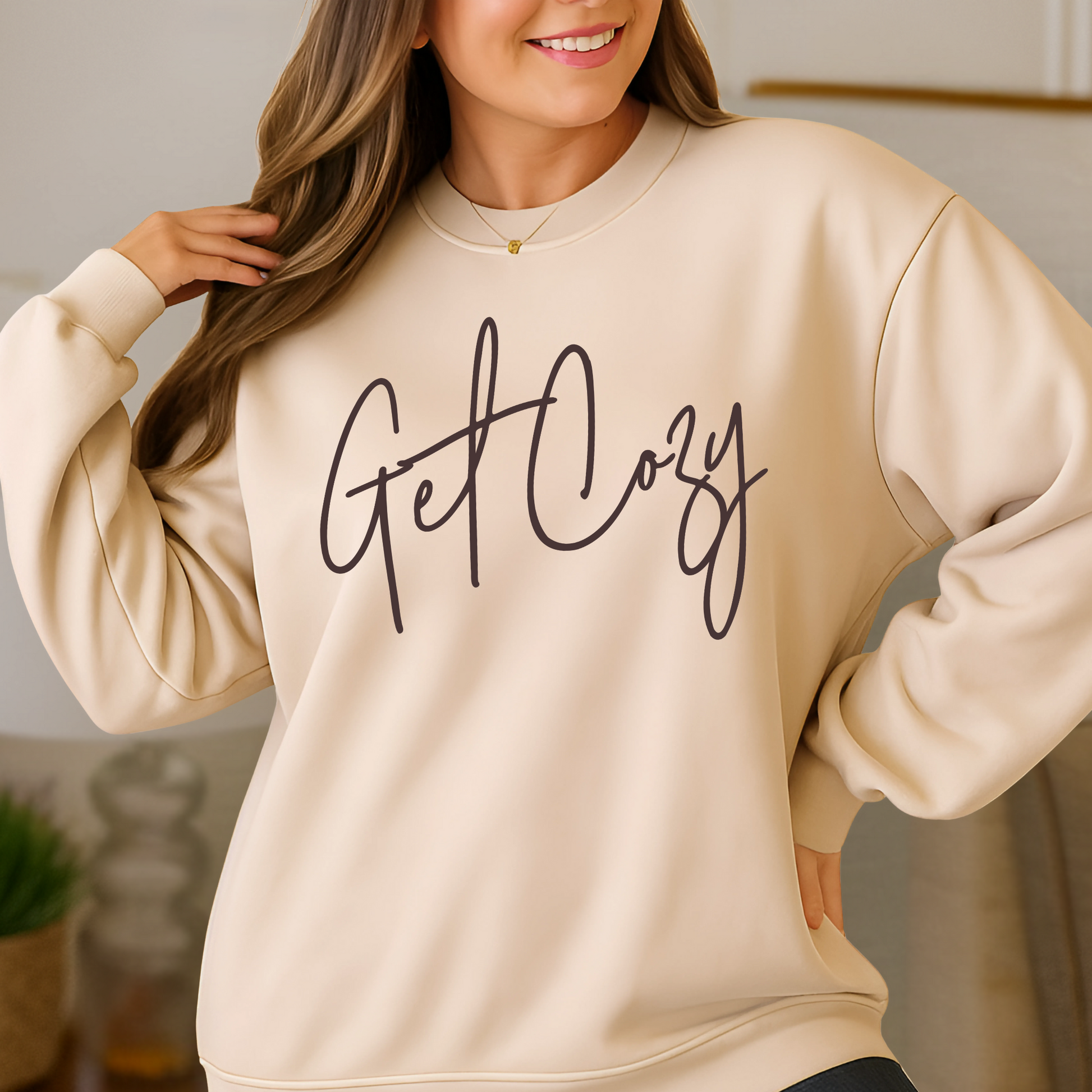 Beige sweatshirt with 'Get Cozy' text worn by a person indoors.