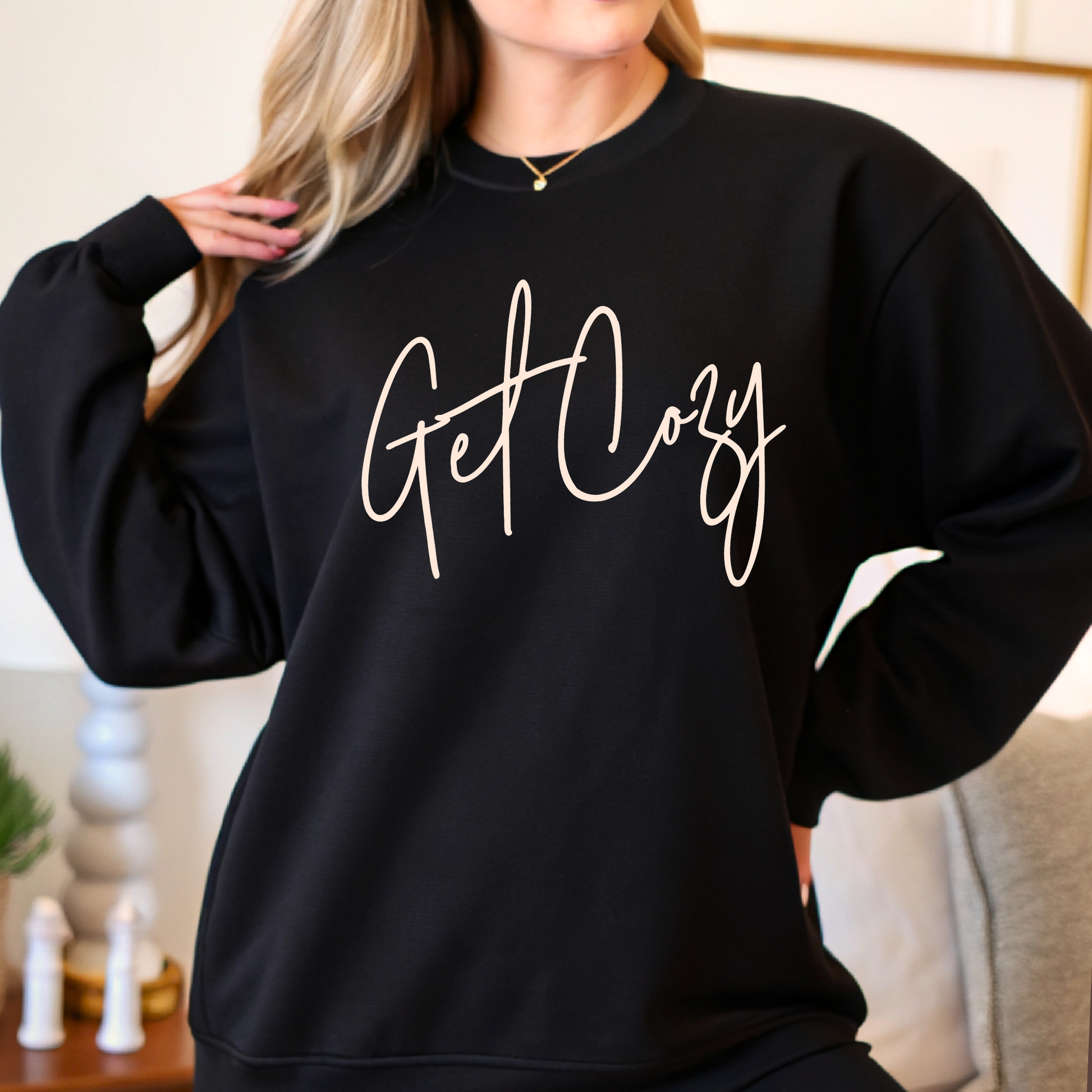 Black sweatshirt with 'Get Cozy' text worn by a person indoors.