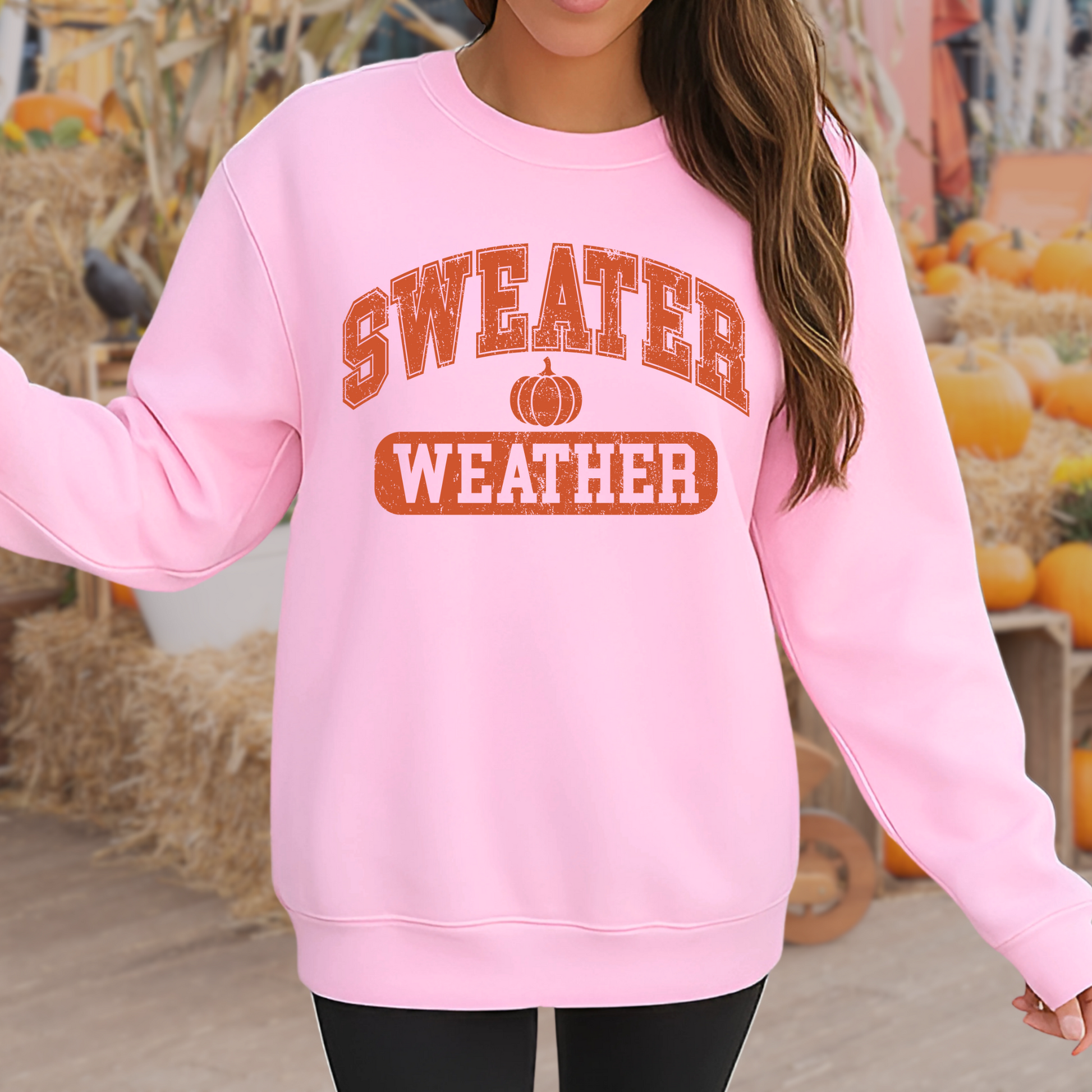 Girl in pink “Sweater Weather” shirt sitting with fall leaves – kids fall outfit
