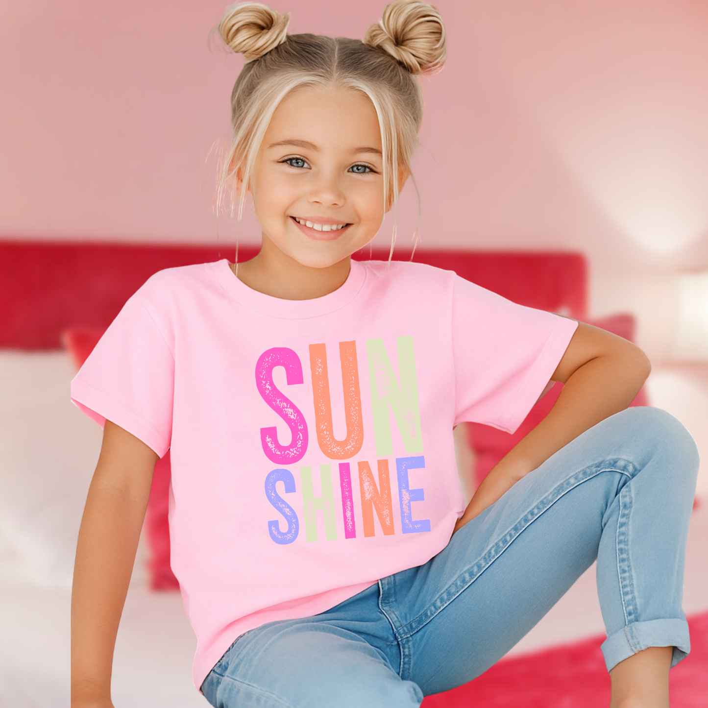 Girl in pink room wearing “Sunshine” tee and jeans