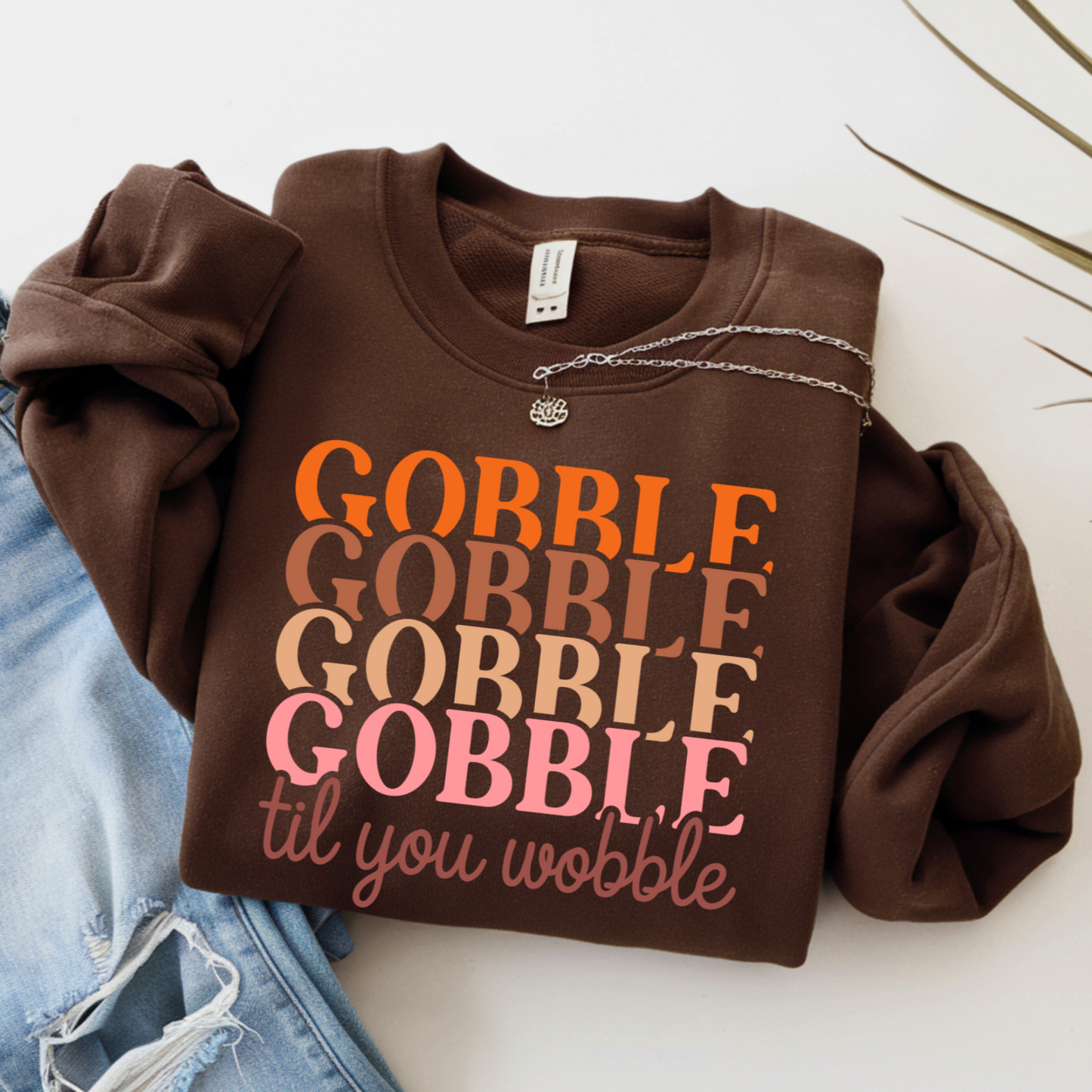 Brown Thanksgiving sweatshirt with 'Gobble Gobble Gobble Gobble til you wobble' text on a white background