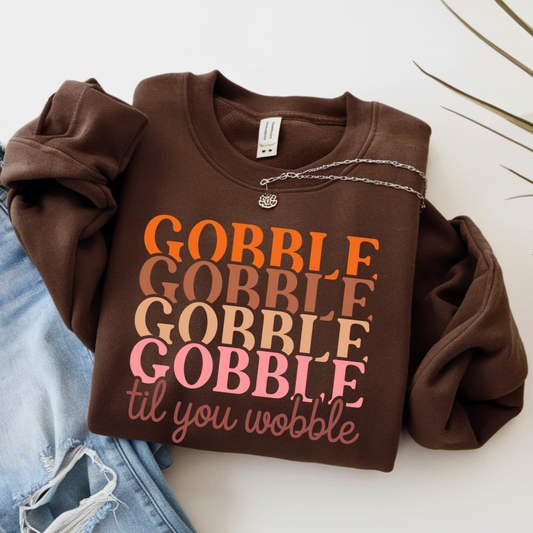 Brown Thanksgiving sweatshirt with 'Gobble Gobble Gobble Gobble til you wobble' text on a white background
