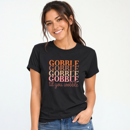 Woman wearing a black T-shirt featuring the stacked “Gobble Gobble Gobble Gobble til you wobble” Thanksgiving design in warm retro colors.