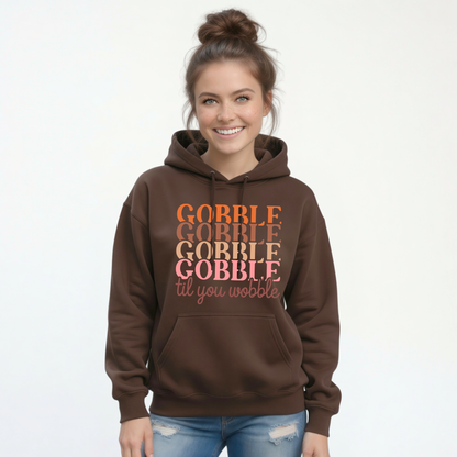 Woman modeling a brown pullover hoodie with the “Gobble Gobble Gobble Gobble til you wobble” Thanksgiving design against a clean white background.