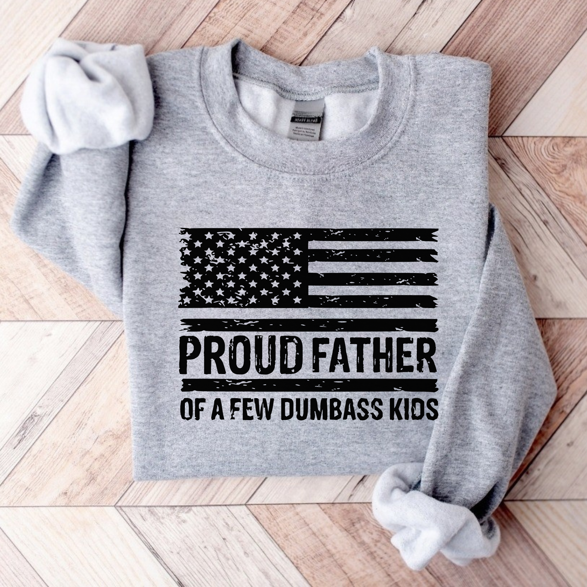 Gray sweatshirt with American flag and text on a wooden surface