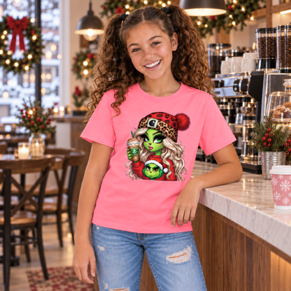 Youth bright pink T-shirt with Boujee Green Girl Christmas graphic, modeled at a holiday decorated café counter