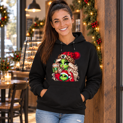 Woman wearing a black hoodie with the Boujee Green Girl Christmas design near a garland-trimmed cafe doorway
