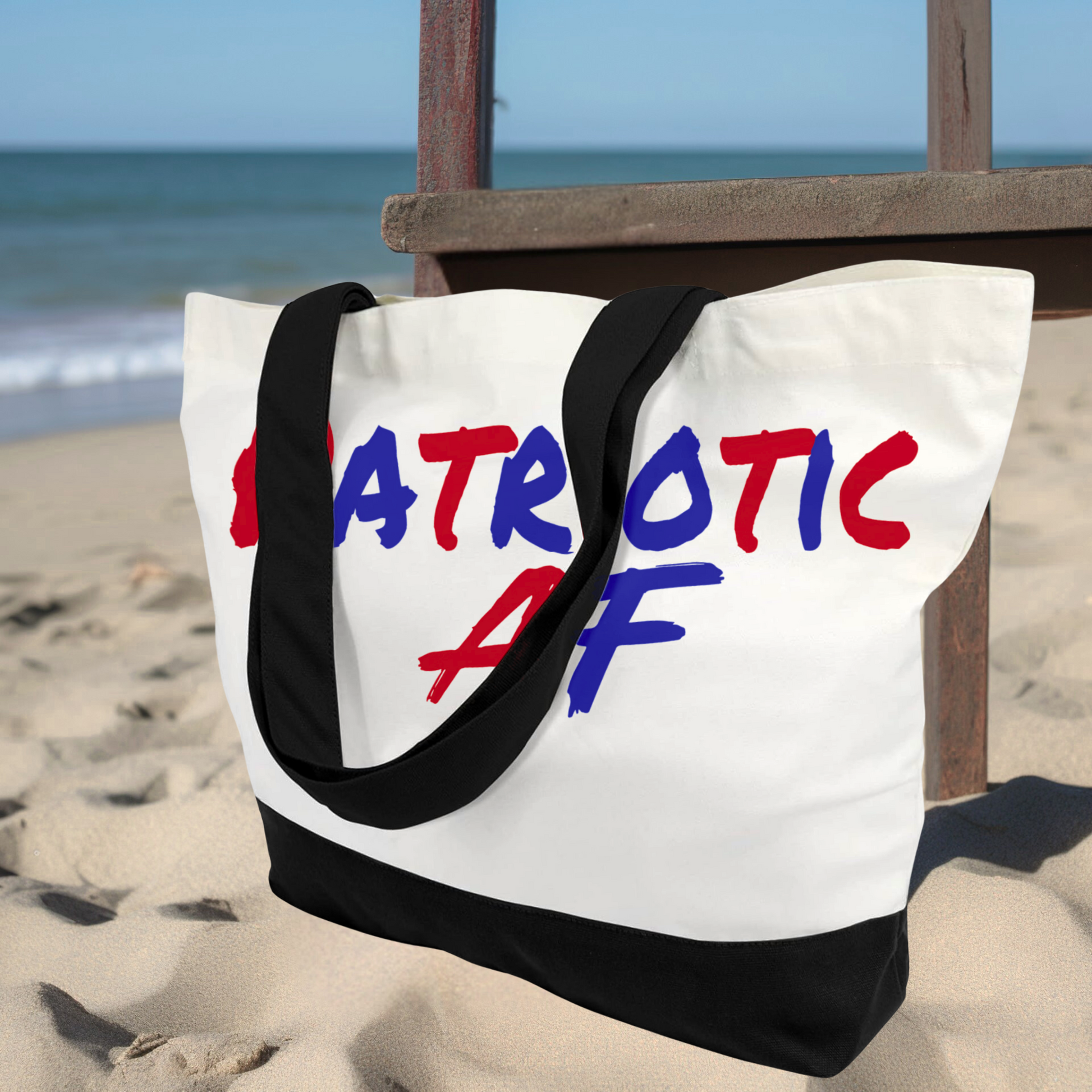 Patriotic AF beach tote with black base and bold lettering on sand