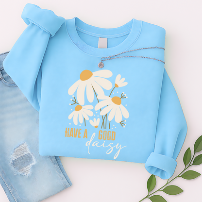Sky blue floral sweatshirt with “Have a Good Daisy” design, laid out with jeans and greenery for a light, playful fall flat lay—perfect for transitional weather and cheerful cozy vibes.