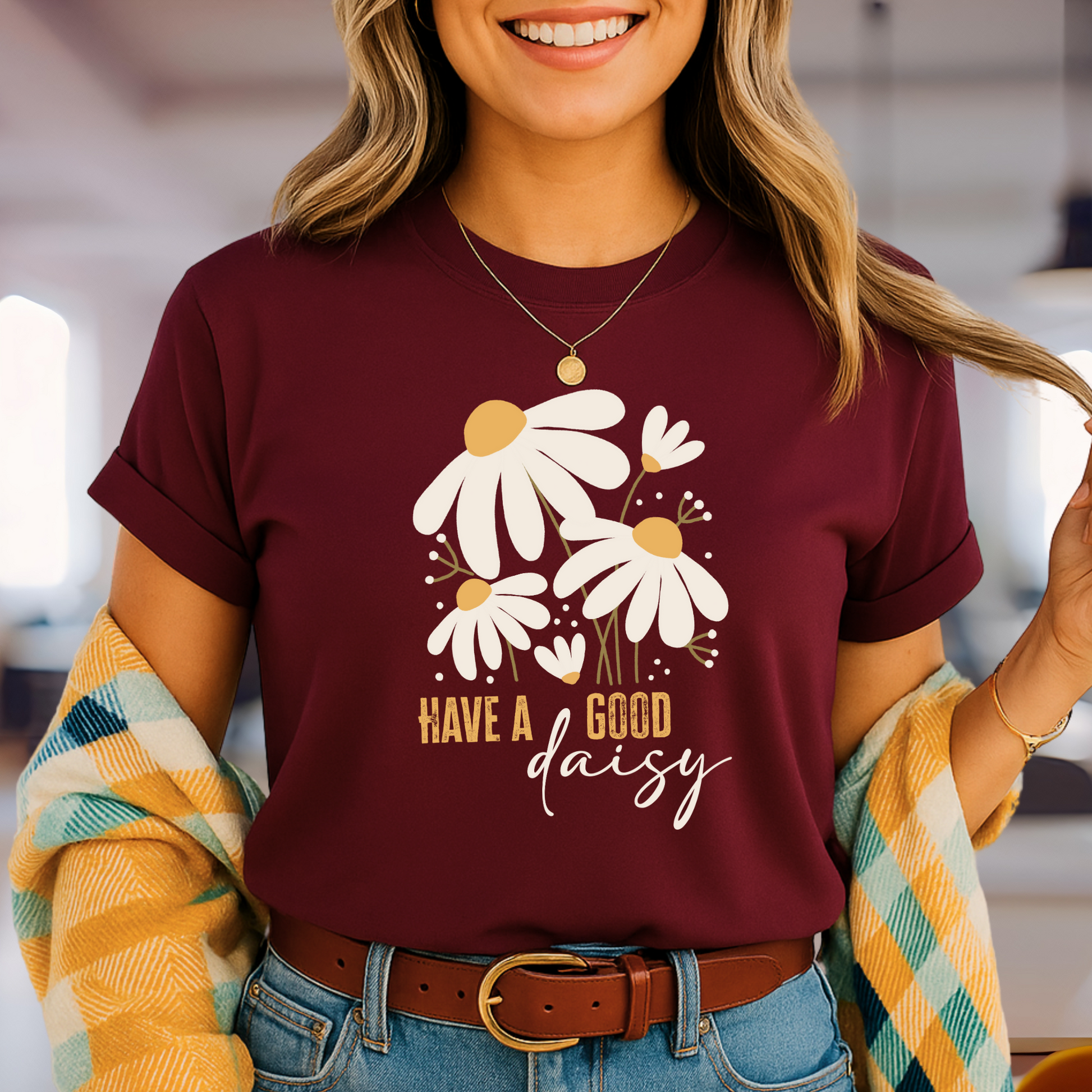 Maroon “Have a Good Daisy” T-shirt with white daisy graphic and retro lettering, styled for fall with warm tones and seasonal outfit layering.