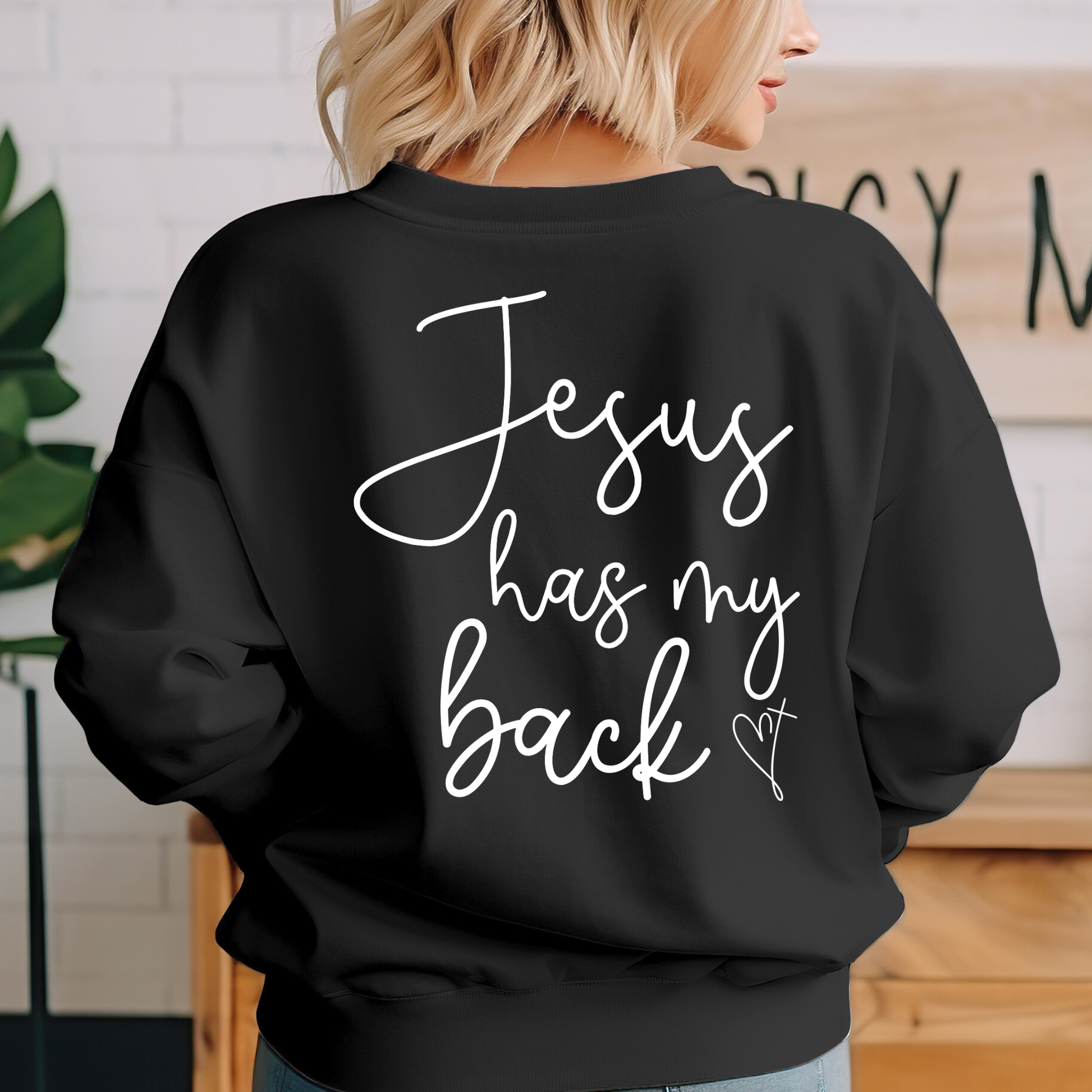 Person wearing a black sweatshirt with 'Jesus has my back' text.