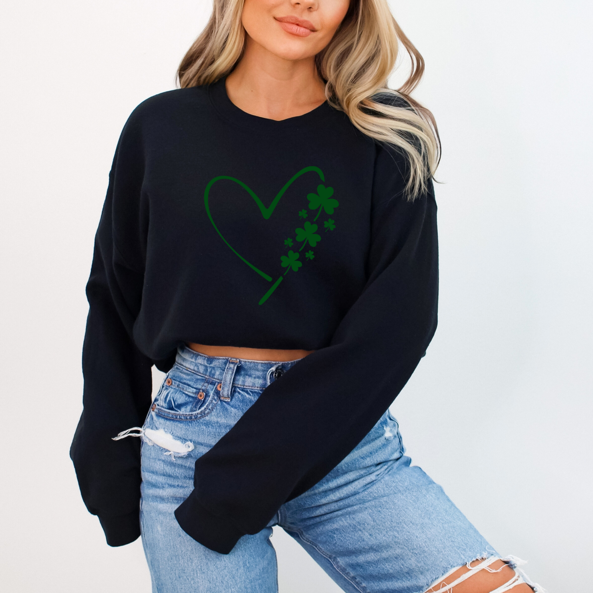 A woman wearing a black sweatshirt with a minimalist green heart and shamrock design, perfect for St. Patrick’s Day celebrations.