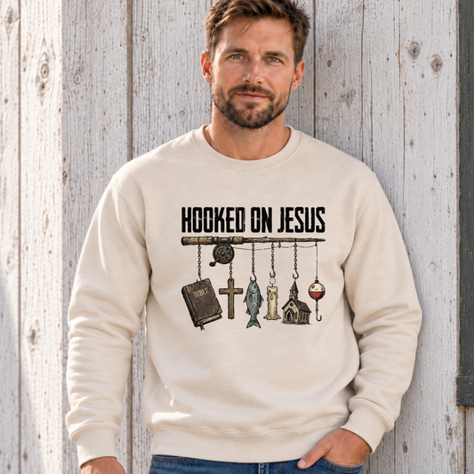 Man wearing a sand colored Hooked on Jesus Creswneck on a lakeside cabin deck.n