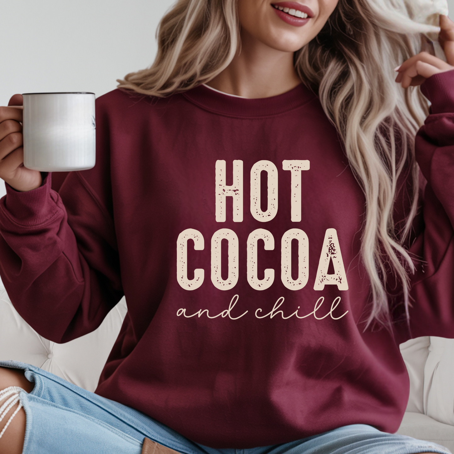Woman wearing a maroon sweatshirt with 'Hot Cocoa and Chill' text, holding a mug.