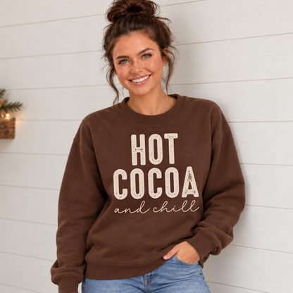 Woman wearing a brown sweatshirt with a cream Hot Cocoa and Chill design against a white shiplap wall