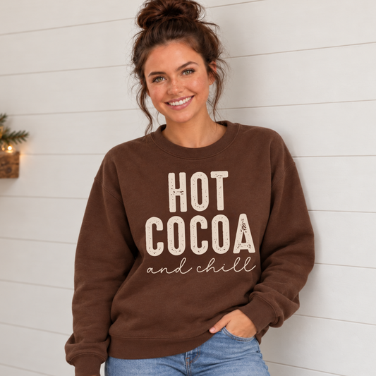Woman wearing a brown sweatshirt with a cream Hot Cocoa and Chill design against a white shiplap wall