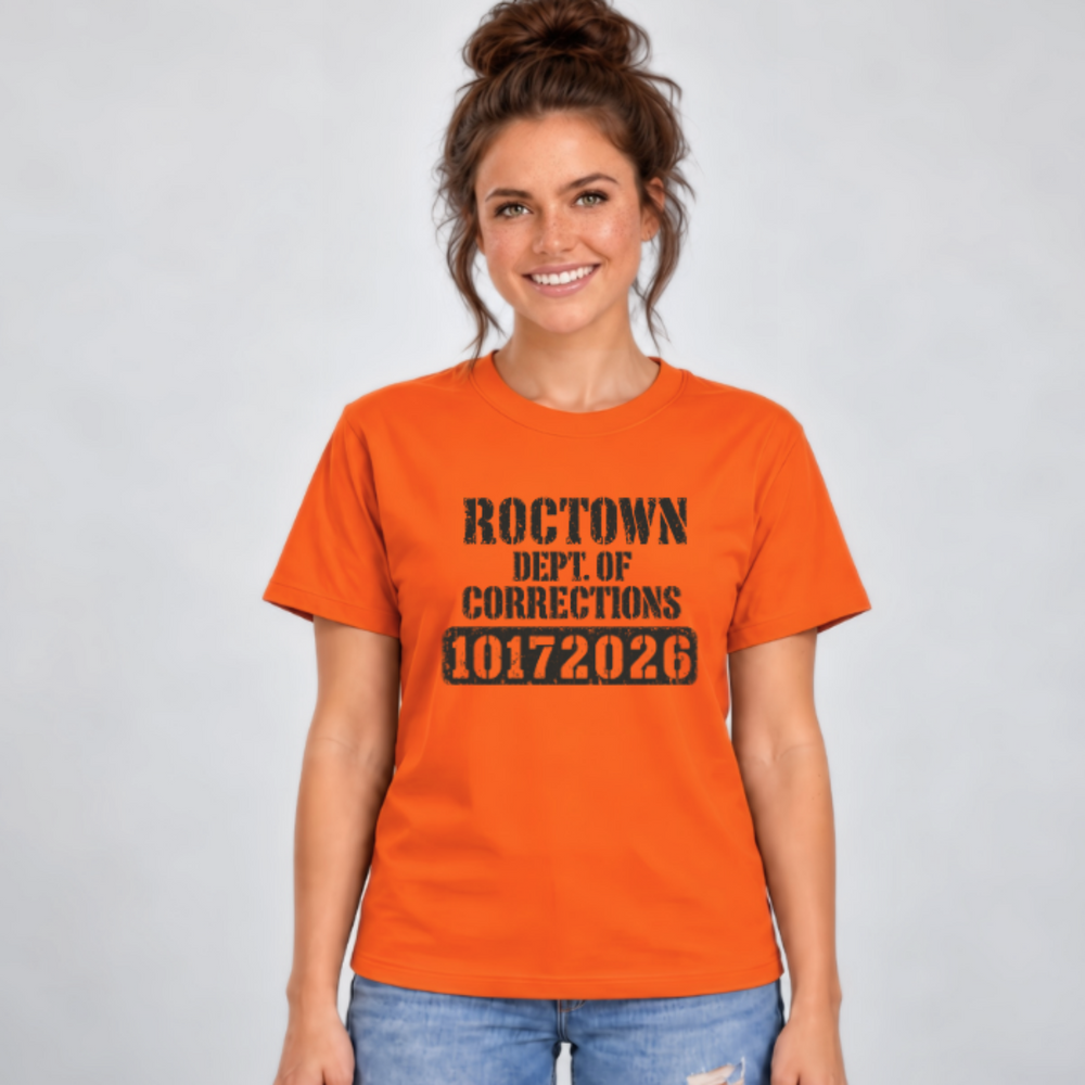 Front view of an orange Roctown parent shirt with worn black Dept. of Corrections lettering and the team number 10172026.