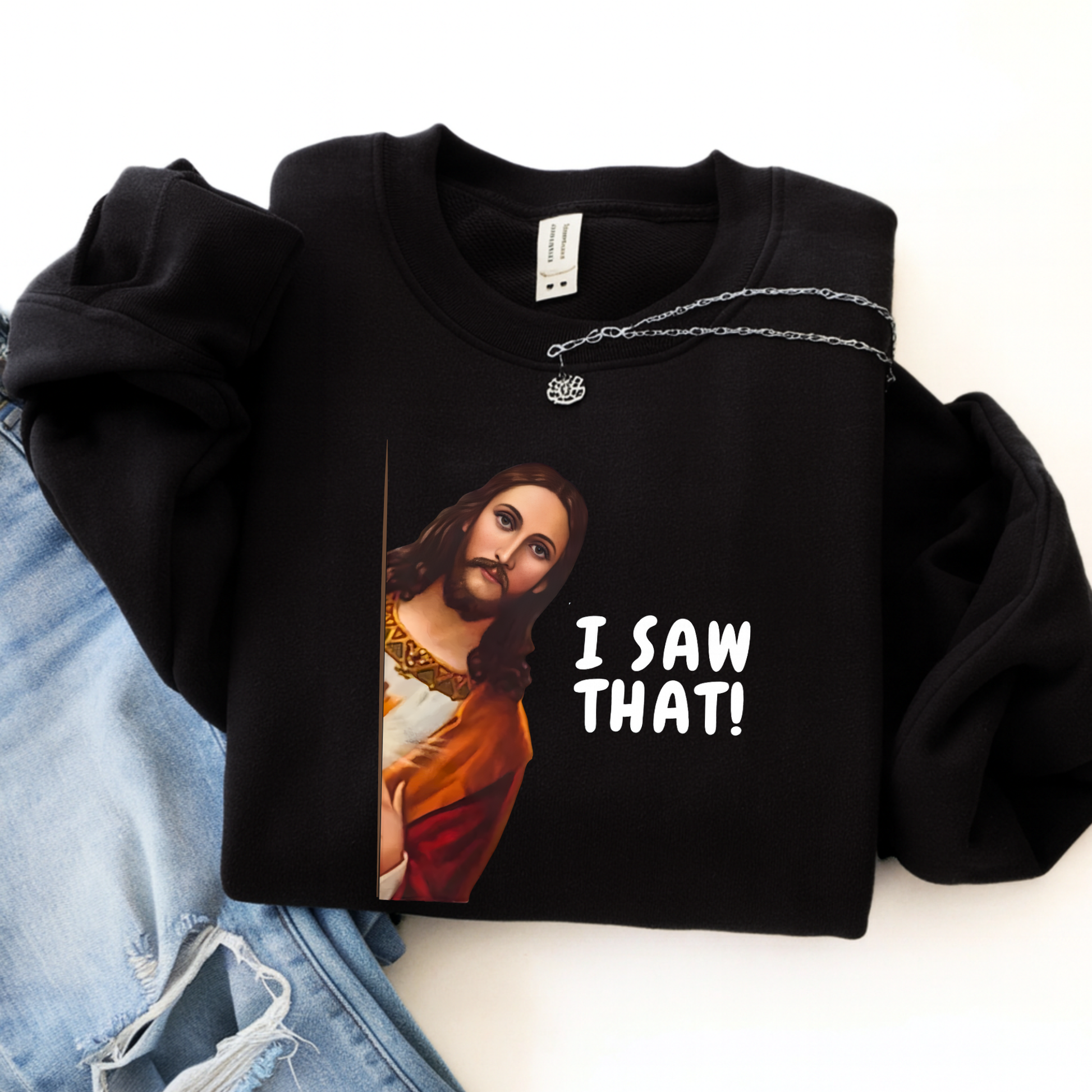 Black sweatshirt with a graphic of a Jesus saying 'I Saw That!' text, displayed with jeans on a white background.