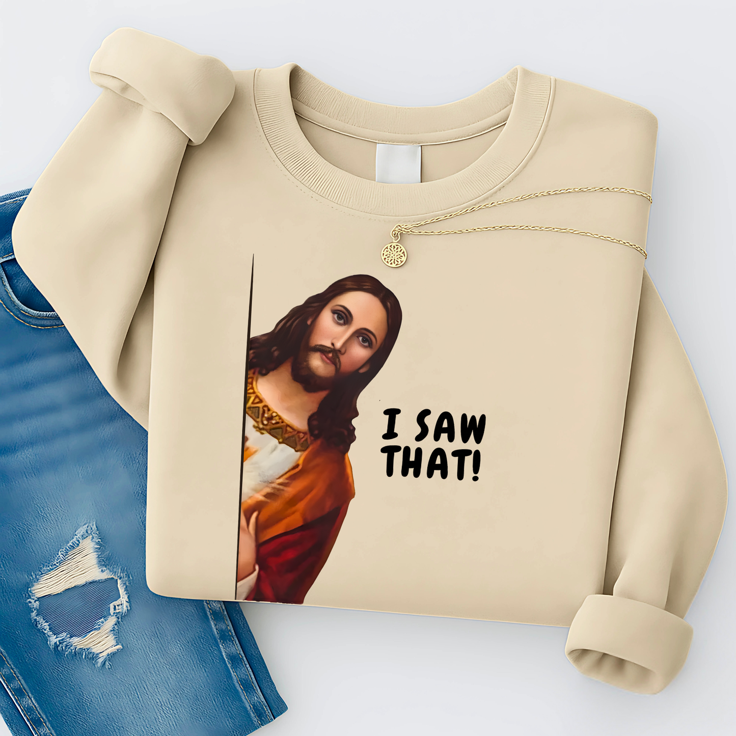 Beige sweatshirt with a graphic of a religious figure and 'I Saw That!' text, on a light blue background.
