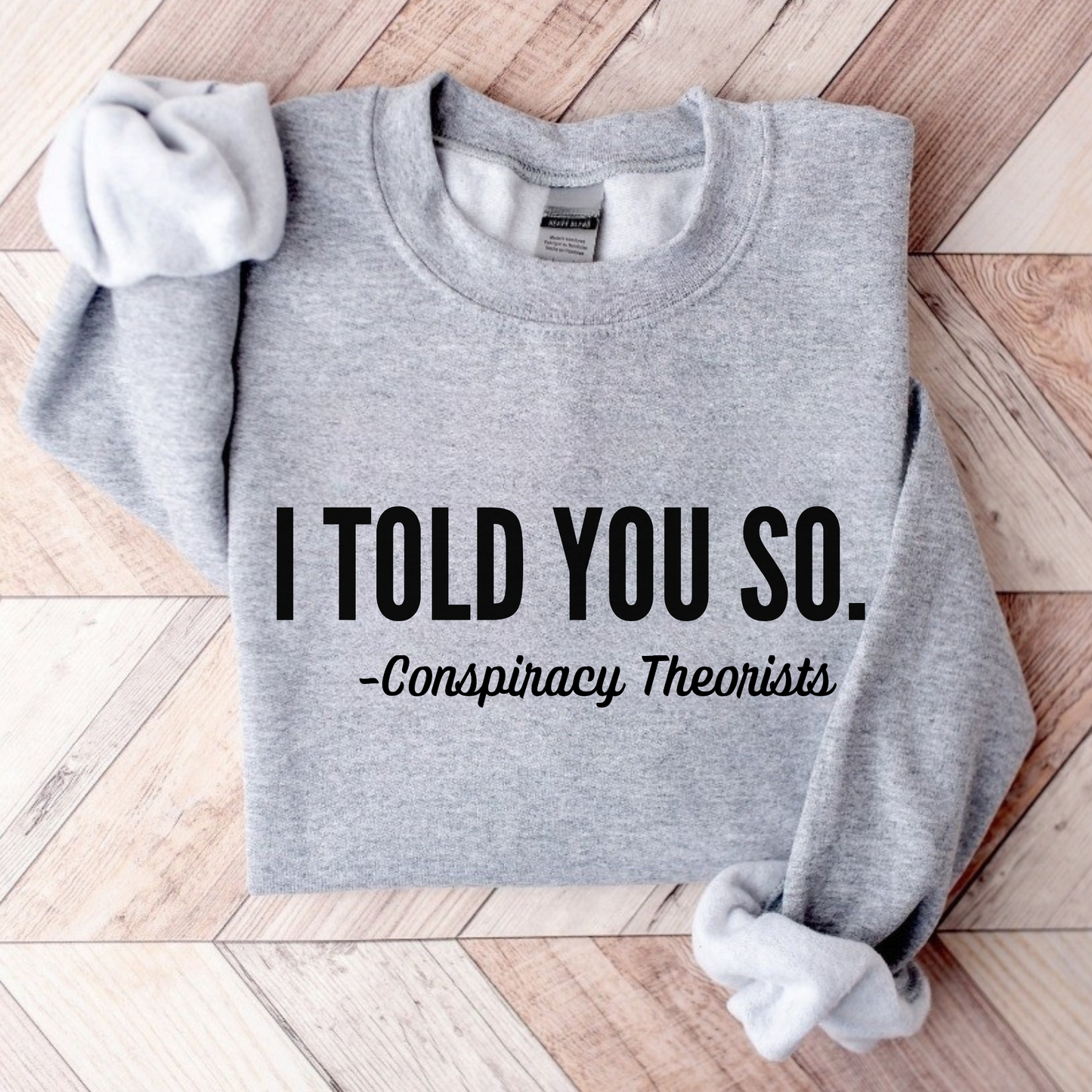 Flat lay gray crewneck sweatshirt showing “I Told You So – Conspiracy Theorists” design