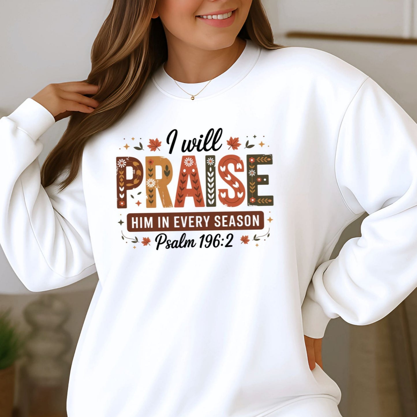 Woman wearing white “I Will Praise Him In Every Season” sweatshirt with Psalm 196:2 design, smiling indoors
