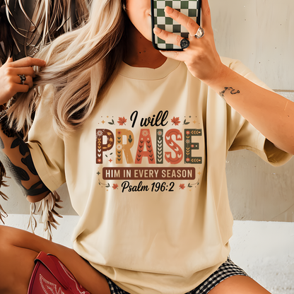Woman wearing sand “I Will Praise Him In Every Season” T-shirt taking mirror selfie with cozy fall aesthetic