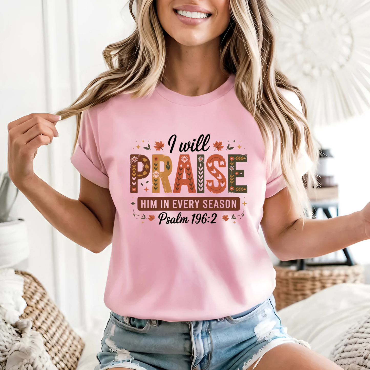 Woman in pink “I Will Praise Him In Every Season” autumn T-shirt smiling indoors
