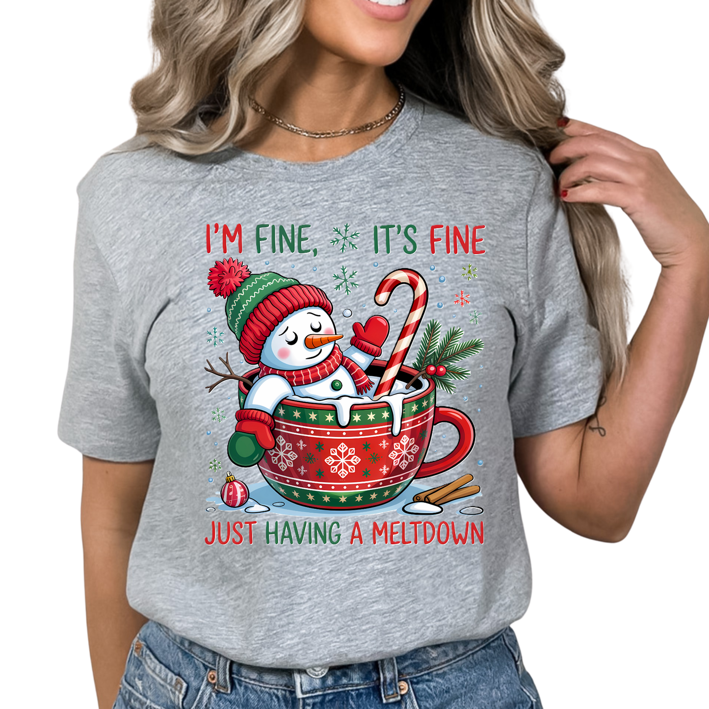 Woman in gray holiday shirt featuring snowman and candy cane cocoa cup graphic.